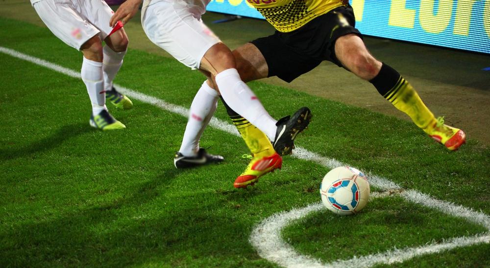 VfB Stuttgart Tickets & Fußballreisen MHP Arena Close Uo Aufnahme eines Tacklings im Spiel Stuttgart gegen Dortmund. Nur Beine und Ball zu erkenn an der Eckfahne