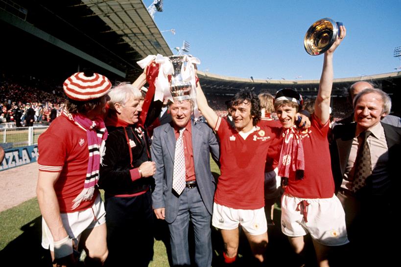 FA Cup Finale 1977 - Liverpool vs Manchester United - Wembley Stadium. Manchester United Manager Tommy Docherty (Mitte) feiert mit Lou Macari (dritter rechts) und Gordon Hill (zweiter rechts) den FA Cup. Foto: PA Images / Alamy Stock Foto